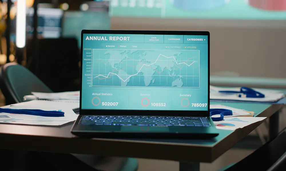 A realistic close-up of a premium laptop on a minimalist white desk with 3D holographic business growth charts emerging from the screen, representing Motive Journey’s (MotiveJourney) AI-powered digital systems for Irish SMEs.